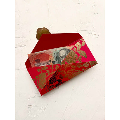 A photo of a red envelope or hongbao or ang pao or lucky packet that is open, showing an Australian twenty dollar note and a premade self adhesive gold wax seal on the open flap. The ang pao design is a traditional Peony pattern in gold foil.