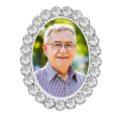 An isolated image of a memorial brooch or memorial pin with crystal diamantes around the edge, in the design called Crystal Oval, isolated on a pure white background. The photo shows an older man. The pin is intended to be attached to a wedding bouquet or wedding outfit to honour a deceased loved one on your wedding day.